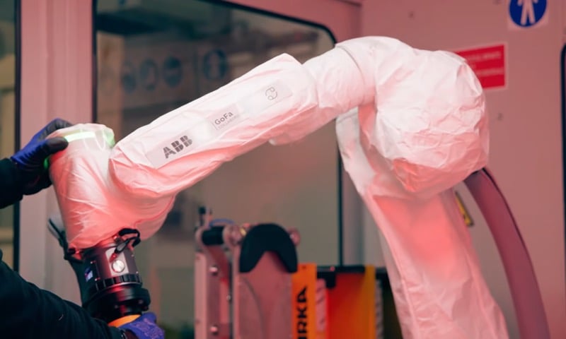A technician moves the ABB GoFa through the finishing motions while it is in the “teach” mode. Notice the protective cover to keep abrasive material out of the cobot’s joints. Image used courtesy of ABB.