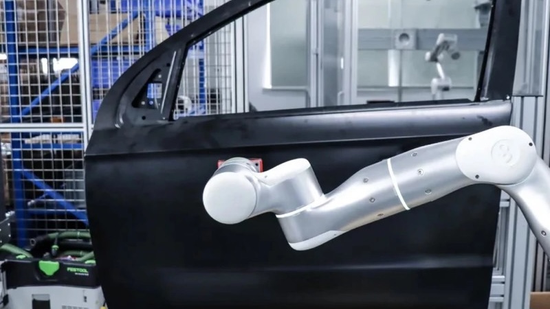 A Flexiv robot being used to sand a car door.