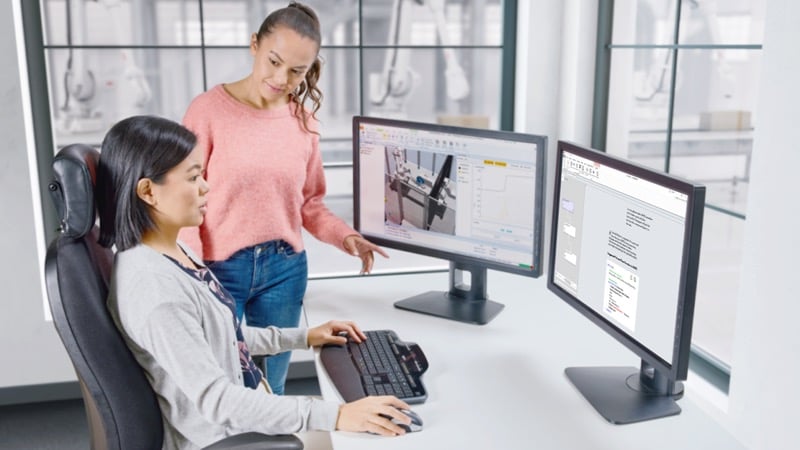 A programmer using RobotStudio to develop robot programs.
